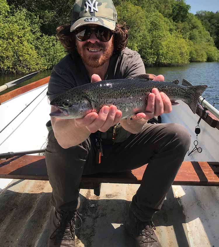 Farlows staff member RIchard fishing for trout Richard holding a trout up whilst in a boat