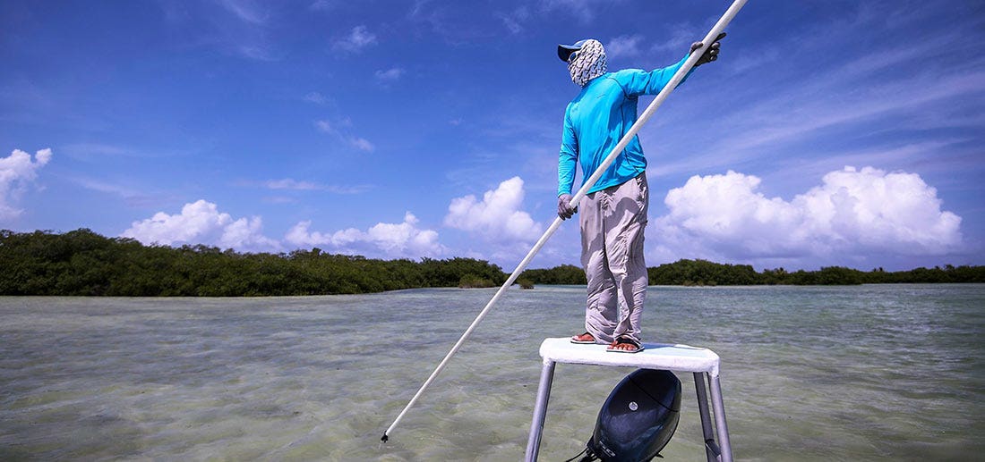 A saltwater guide poles a fishing skiff