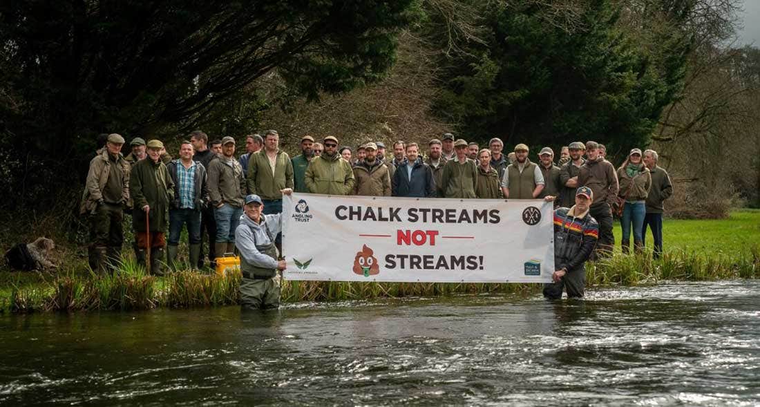 Anglers Against Pollution Demo on the River Test Anglers holding up a banner saying Chalk Streams not Poo Streams
