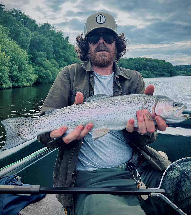 Richard with his trout catch Richard holding a trout up whilst in a boat